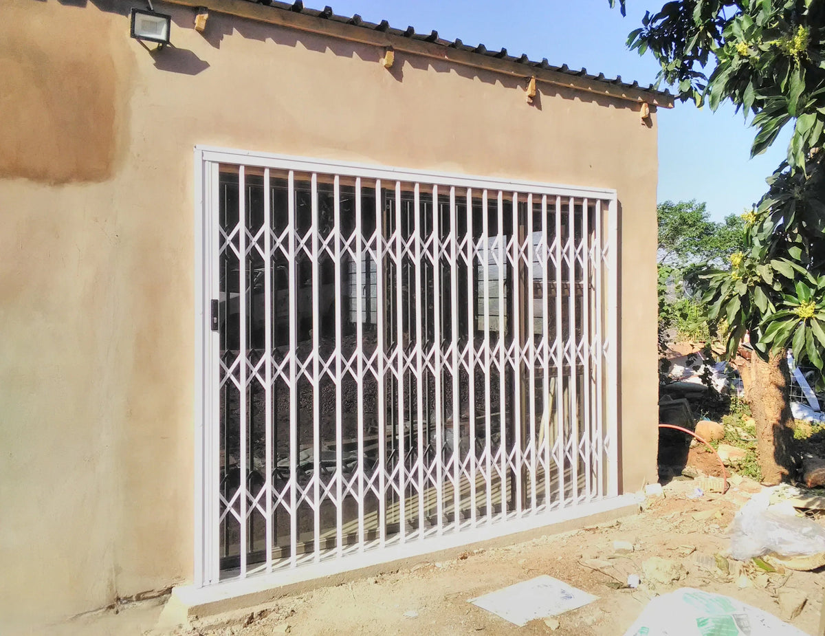 White aluminium retractable security gate installed across a wide residential doorway