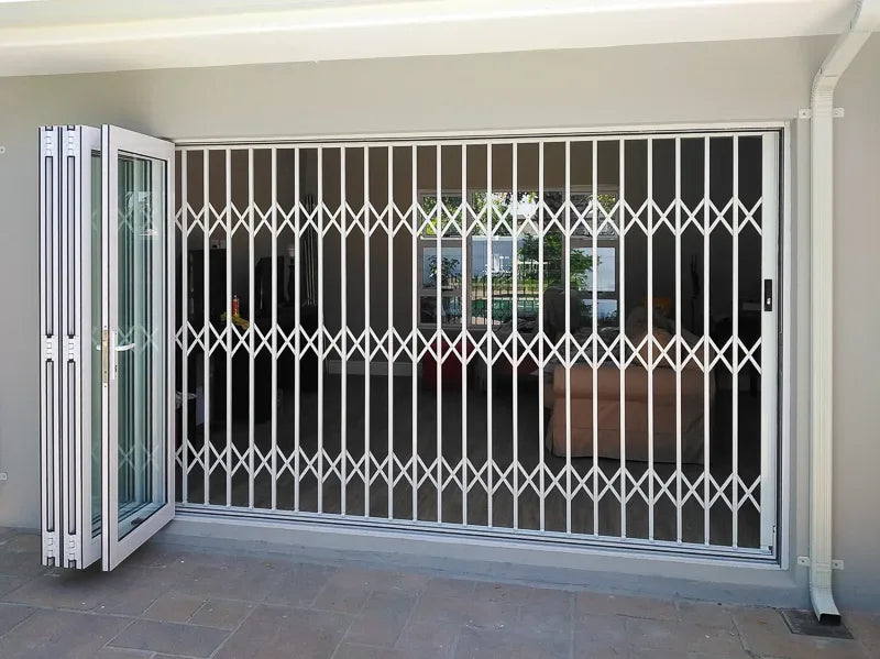 White aluminium retractable security gate installed across a wide residential doorway