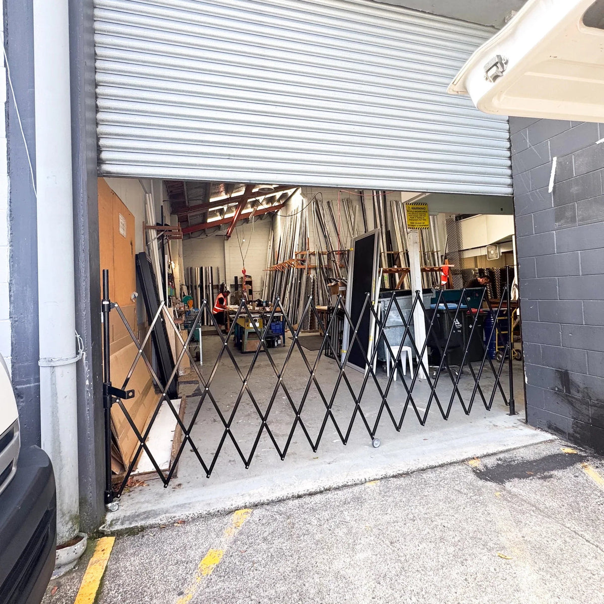 Black expandable barrier with adjustable scissor gate design for pedestrian access control and safety management