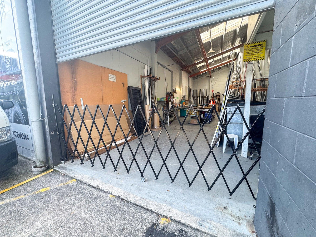 Black expandable barrier with adjustable scissor gate design for pedestrian access control and safety management