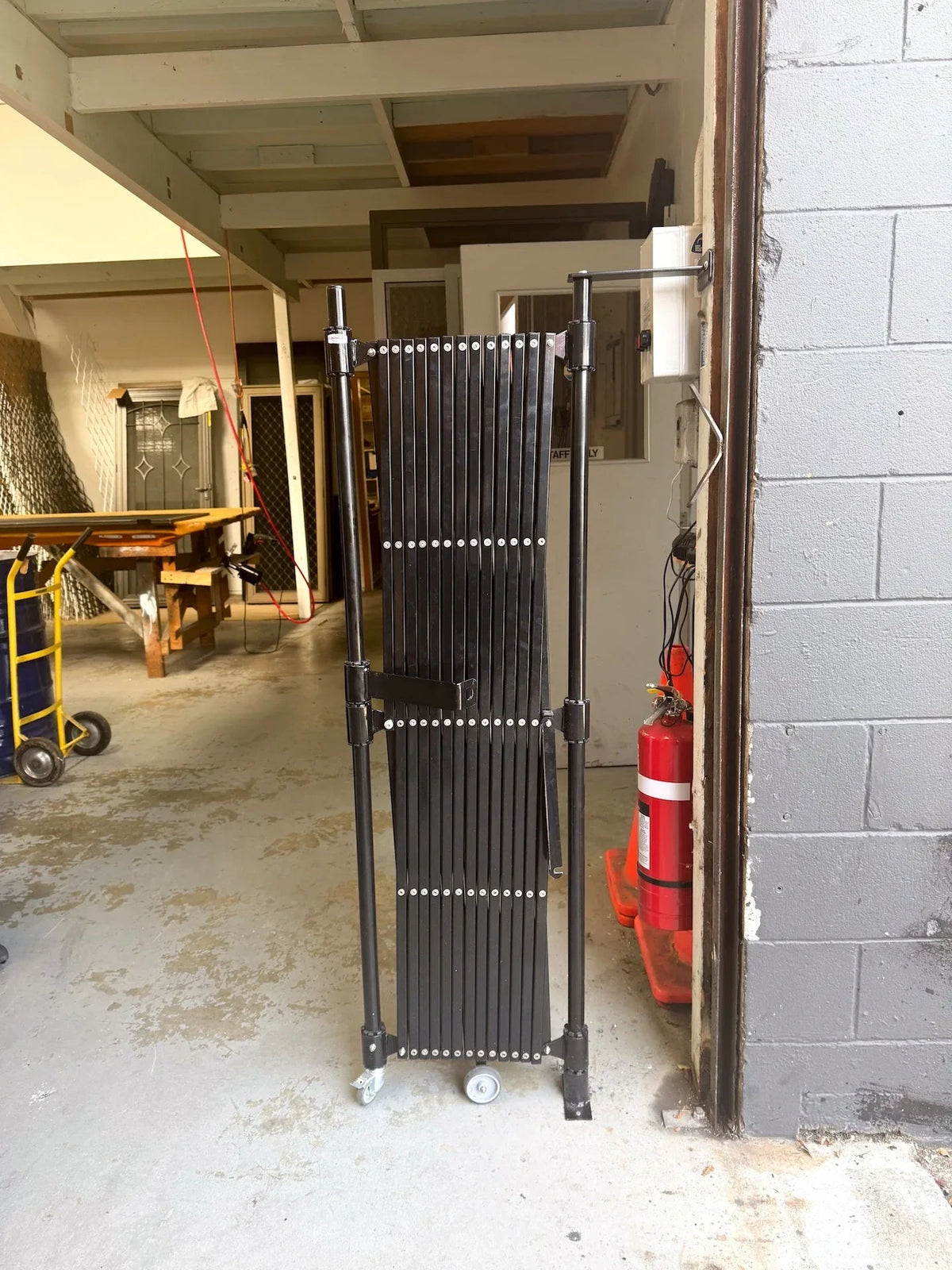 Black expandable barrier with adjustable scissor gate design for pedestrian access control and safety management
