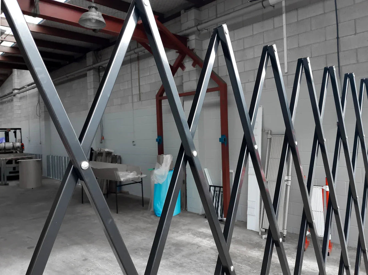 Black expandable barrier with adjustable scissor gate design for pedestrian access control and safety management