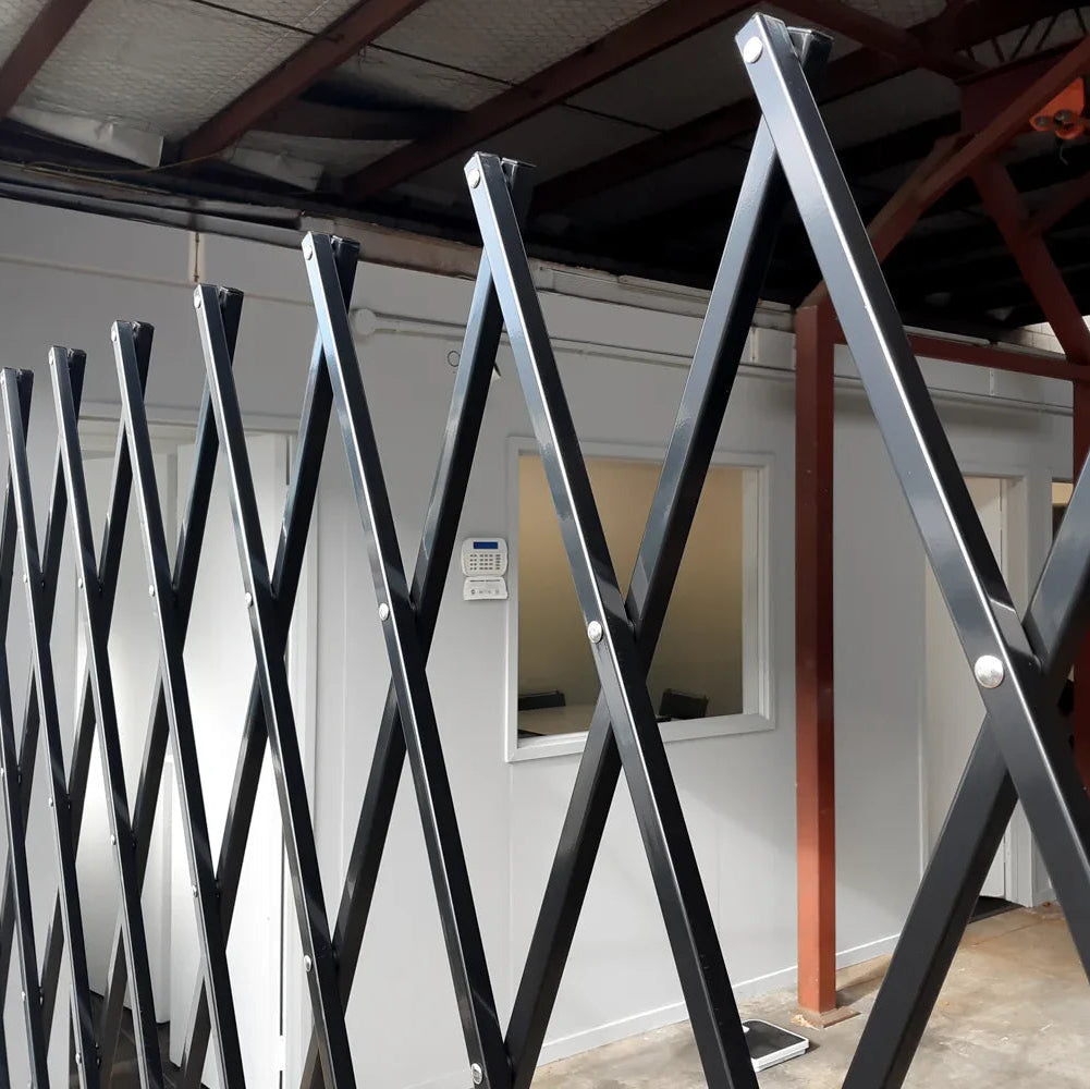 Black expandable barrier with adjustable scissor gate design for pedestrian access control and safety management