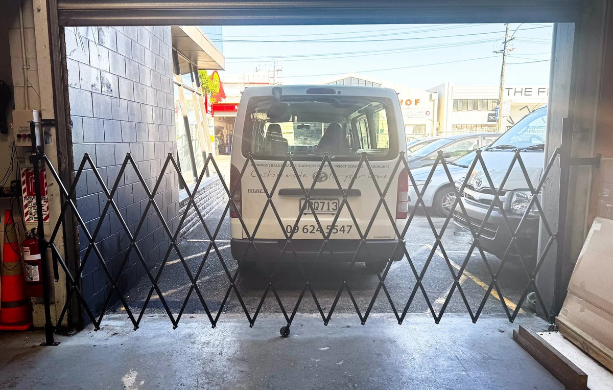 Black expandable barrier with adjustable scissor gate design for pedestrian access control and safety management