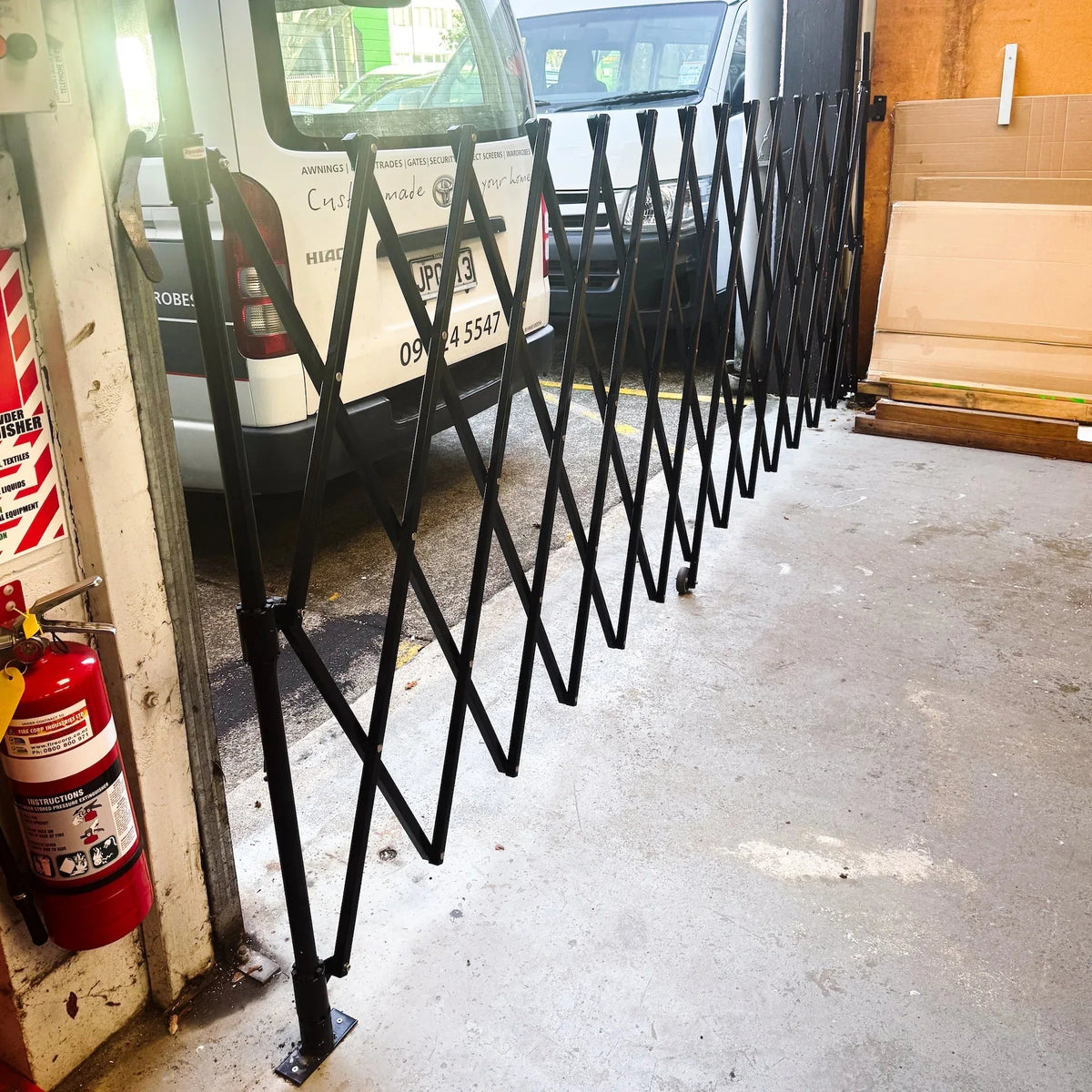 Black expandable barrier with adjustable scissor gate design for pedestrian access control and safety management