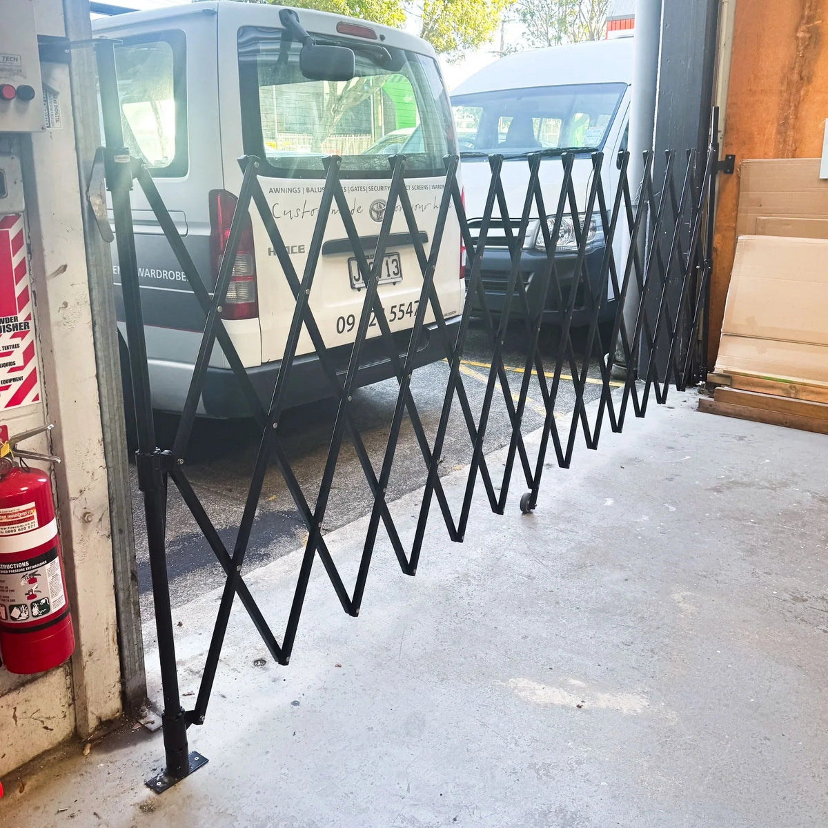 Black expandable barrier with adjustable scissor gate design for pedestrian access control and safety management
