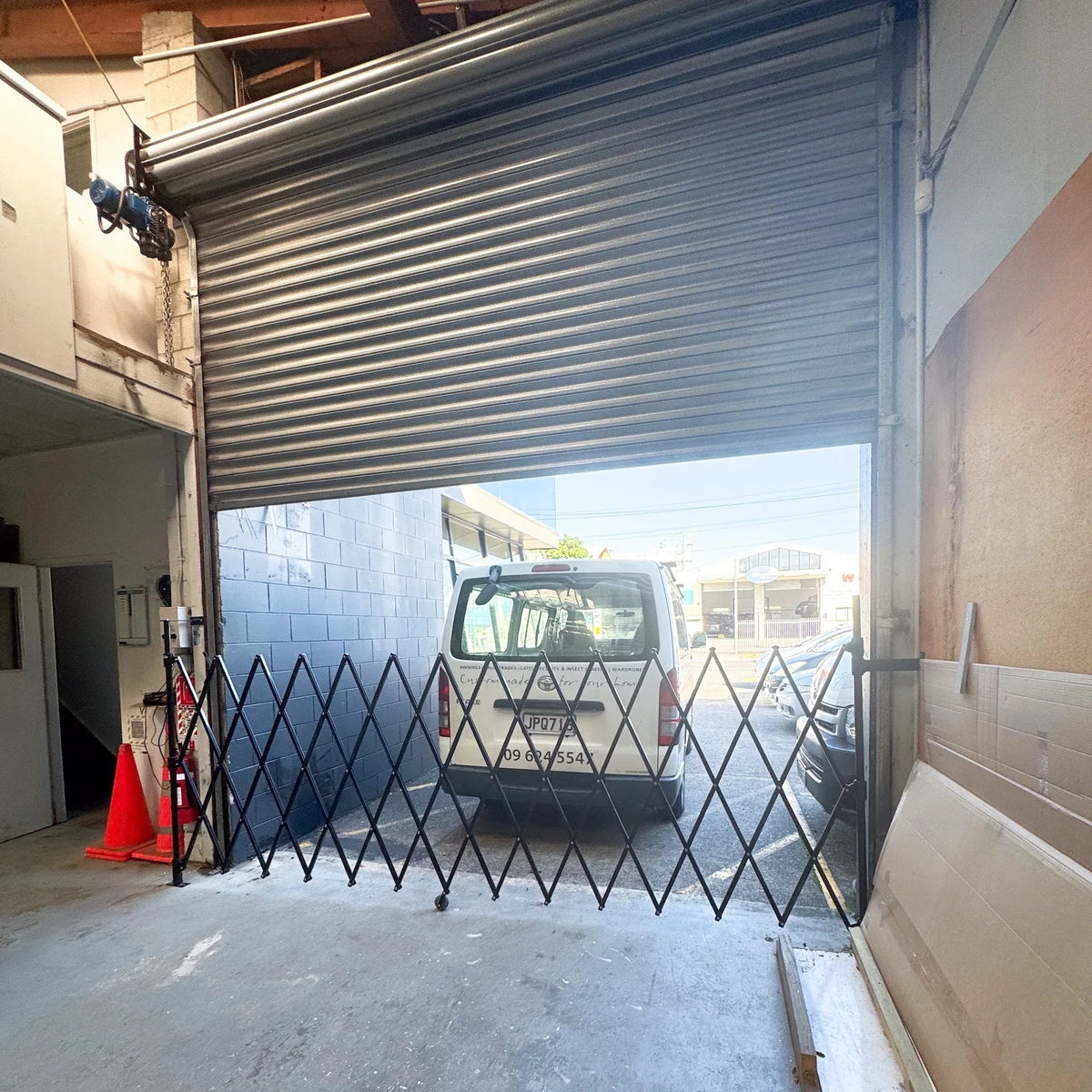 Black expandable barrier with adjustable scissor gate design for pedestrian access control and safety management