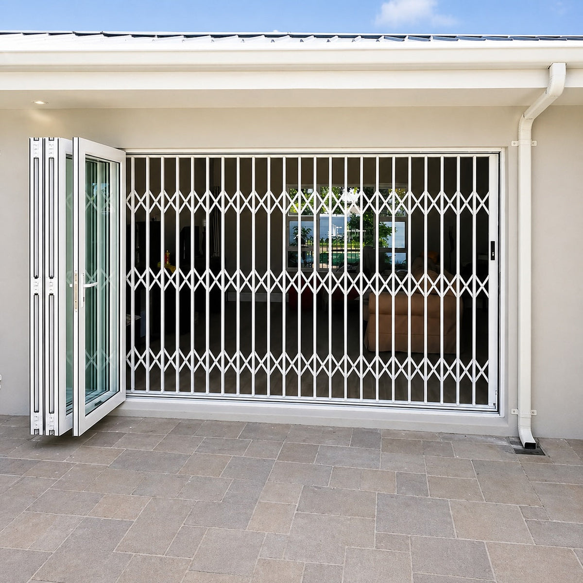 White aluminium retractable security gate installed across a wide residential doorway