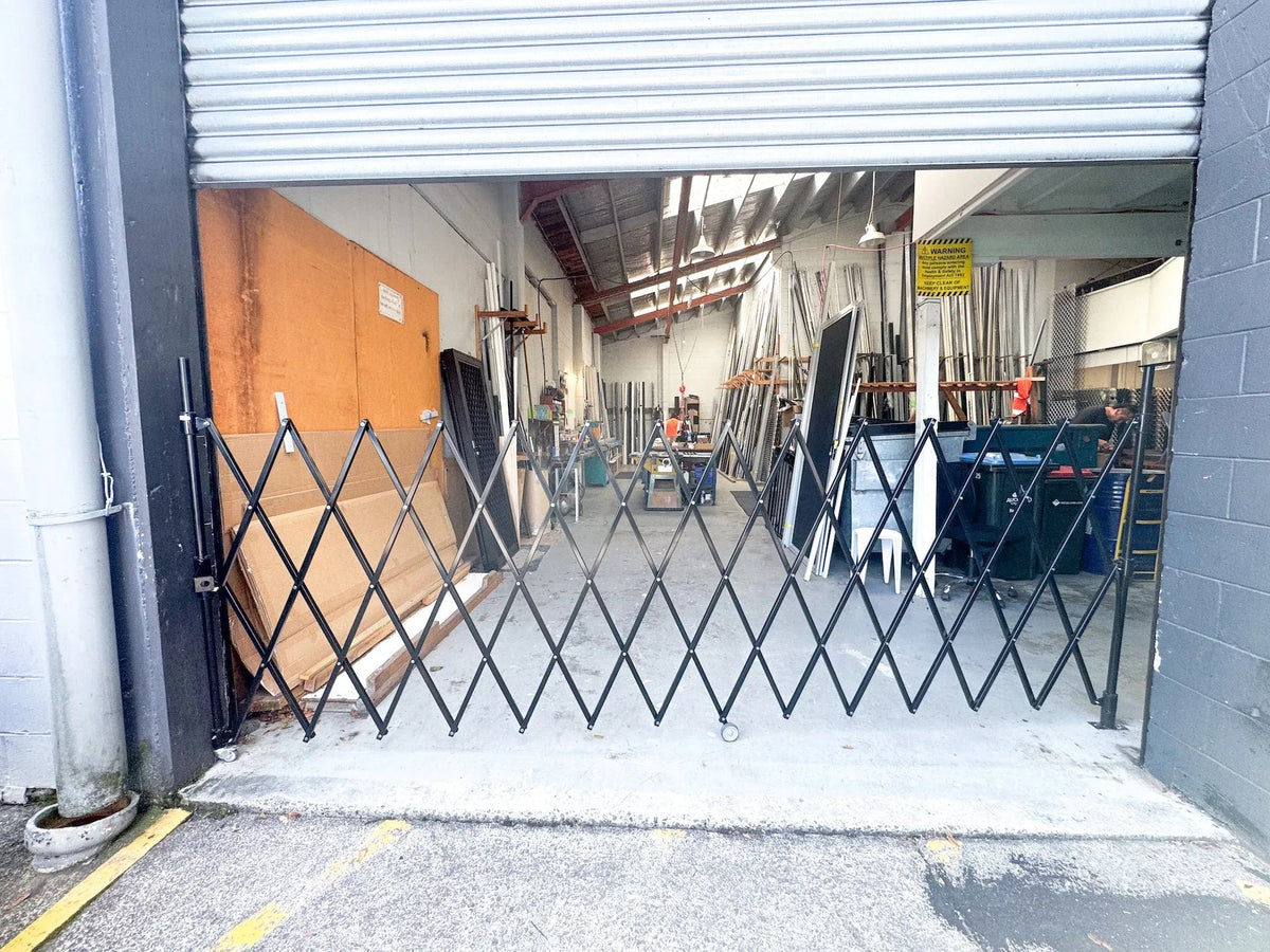 Black expandable barrier with adjustable scissor gate design for pedestrian access control and safety management